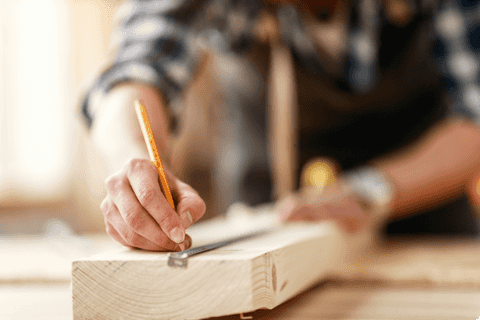 man measuring plank of wood